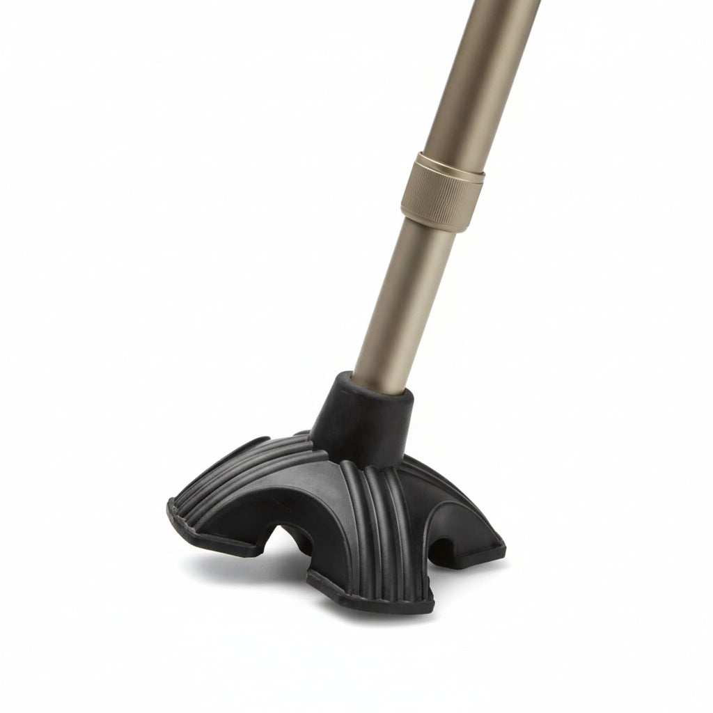 Walking stick fitted with Max Mobility Alpha Quad‑Leg Cane Tip standing upright on a flat floor